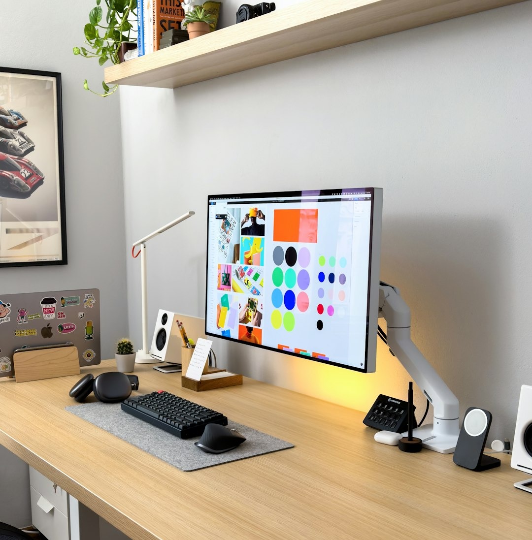 Modern home office desk with computer, laptop, and design software.